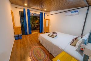 a bedroom with a white bed and a wooden floor at Simrose in Agonda