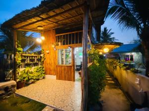una casa con una puerta y un porche con plantas en Joyful Hut with Netflix and Perfect Sunrise View Maya, Daanbantayan, 