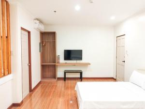 a white room with two beds and a tv at Eekos Bed and Breakfast in Baguio