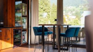 eine Bar mit blauen Stühlen, einem Tisch und einem Fenster in der Unterkunft Sonne 1806 - Hotel am Campus Dornbirn in Dornbirn