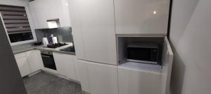 uma cozinha com armários brancos e um micro-ondas em Apartament CENTRUM em Sosnowiec