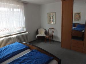 een slaapkamer met een bed, een raam en een stoel bij Haus Alpenblick in Immenstaad am Bodensee