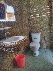 a bathroom with a stone wall with a toilet and a sink at Cliff View Bungalows in Ko Chang