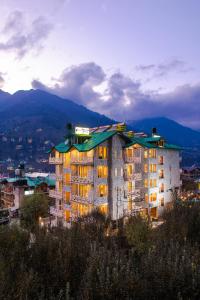 um grande edifício com as suas luzes acesas numa cidade em Tripli Hotels Stone House Cottage em Manali