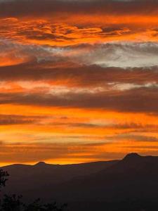 einen Sonnenuntergang mit Bergen im Hintergrund in der Unterkunft Apartamento rural El Pastor es un estudio con gran ventanal a Gredos in Cabezas Bajas