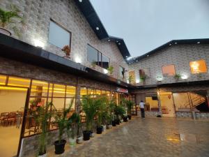 a man standing in front of a building with potted plants at Hotel Aurelia Pearl in Patna