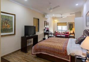 a hotel room with a bed and a tv at Neelam Bed & Breakfast in Kolkata