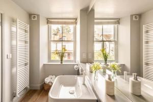 a white bathroom with a sink and two windows at Shamrock, Bowness on Windermere, Superb one bedroom apartment with private parking in Bowness-on-Windermere +11 photos
