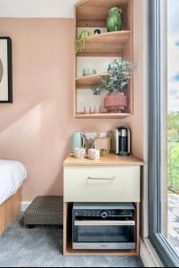 a small cabinet with a microwave in a bedroom at Travellers Tales - A Pod in the Cotswolds in Minster Lovell