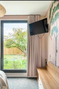 a living room with a large window and a television at Travellers Tales - A Pod in the Cotswolds in Minster Lovell