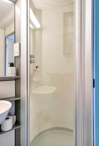 a bathroom with a glass shower with a sink at Travellers Tales - A Pod in the Cotswolds in Minster Lovell