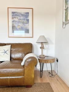 a living room with a brown leather couch and a table at The Beach House Broadstairs in Broadstairs