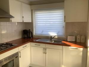 cocina con armarios blancos, fregadero y ventana en Coco's Beach Resort, en Sint Annaland