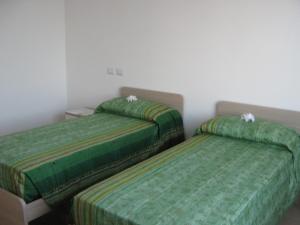 two beds in a room with green sheets at B&B Stazione in Canegrate