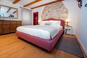a bedroom with a large bed and a stone wall at Apartments Casa De Amicis in Rovinj