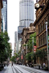 a busy city street with a clock on a building at A by Adina Sydney in Sydney