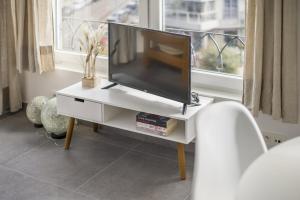 una televisione su supporto bianco in una stanza con finestra di Panne a Côte a De Panne