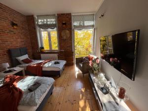 a living room with a couch and a bed and a tv at Apartament przy Ratuszu in Barczewo