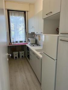 una piccola cucina con elettrodomestici bianchi e una finestra di Senza Pensieri via Viviani a Crema