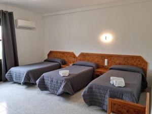 Habitación de hotel con 3 camas y toallas. en Hostal La Reserva, en Cobeña