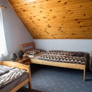 two beds in a room with a wooden ceiling at Berger Pince-vendégház, Hajósi pincék in Hajósi Pincék