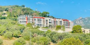 un gran edificio de apartamentos en una colina con árboles en Ajaccio T2 grand standing neuf - centre ville et plages - 4 personnes - parking privé, en Ajaccio
