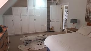 a bedroom with a white bed and white cabinets at Mountain View Self-Catering Apartment in Somerset West