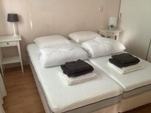 2 camas con almohadas blancas y toallas negras. en Coco's Beach Resort, en Sint Annaland