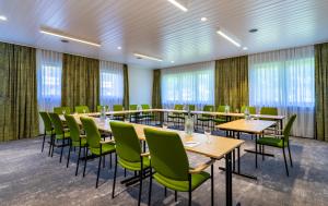 uma sala de conferências com mesas, cadeiras e janelas em Das Wiesgauer - Alpenhotel Inzell em Inzell