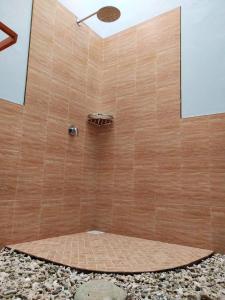 a shower with a brown tile wall and a shower head at Saima Inn in Maalhos