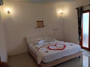 a bedroom with a white bed with red decorations on it at Saima Inn in Maalhos