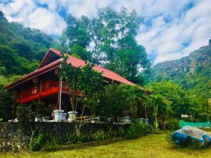ein rotes Haus mit einem roten Dach und einem Berg in der Unterkunft Cat Ba Eco Lodge Resort in Cát Bà
