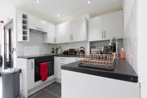 a kitchen with white cabinets and a black counter top at Beautiful flat next to city centre in Liverpool
