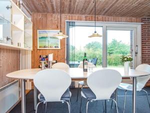 uma sala de jantar com mesas e cadeiras brancas e uma grande janela em 8 person holiday home in Glesborg em Bønnerup