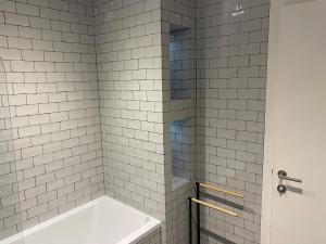 a white tiled shower with a tub in a bathroom at 1 The Bay - Stunning contemporary flat on the Scottish coast in Coldingham