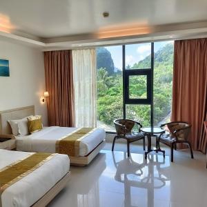 a hotel room with two beds and a large window at One El Nido Suite in El Nido