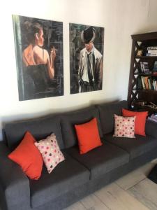 AnaMar Eternity House في Asprókambos: أريكة سوداء مع وسائد ملونة وصور على الحائط