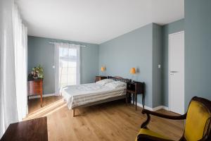 - une chambre avec des murs bleus, un lit et un bureau dans l'établissement Le Herpin Cancale, à Cancale