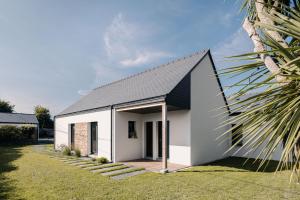 une maison blanche avec un toit noir dans l'établissement Le Herpin Cancale, à Cancale