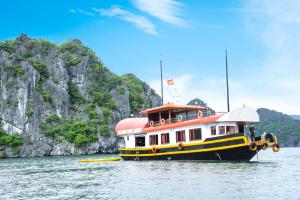 Cat Ba Bay Cruises في كات با: قارب في الماء بجانب جبل