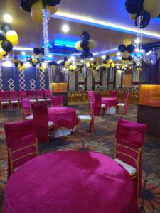 sala bankietowa z fioletowymi stołami, krzesłami i balonami w obiekcie Hotel APJ GRAND w mieście Faridabad