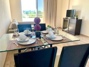 uma sala de jantar com uma mesa com pratos e copos em Nissi 3 C14 Sea View Top Floor Apartment em Agia Napa