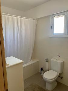 uma casa de banho branca com um WC e uma janela em Nissi 3 C14 Sea View Top Floor Apartment em Agia Napa