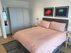 a bedroom with a large bed with pink pillows at 1 The Bay - Stunning contemporary flat on the Scottish coast in Coldingham