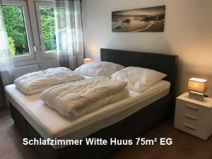 ホークジールにあるWitte Huus 75m_ und 51m_ Ferienwohのベッドルーム1室(白い枕付)