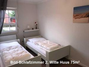 a small bedroom with two beds and a window at Witte Huus 75m_ und 51m_ Ferienwoh in Hooksiel
