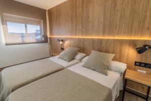 two beds in a room with wooden walls and a window at Hotel Kika in Santa Marta