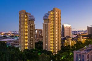 two tall buildings in a city at night at Belgravia Serviced Residence Wuxi in Wuxi