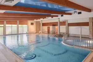 a large indoor swimming pool with blue water at Artis Hotel & Spa in Zamość