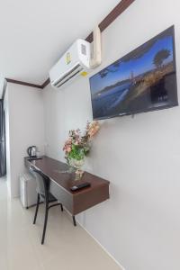The Chic Patong في شاطيء باتونغ: غرفة مع طاولة وتلفزيون على الحائط